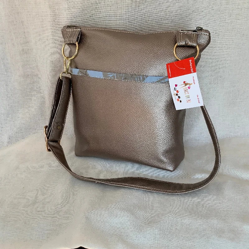 Crossbody bag with a hidden anti - theft pocket for securityMetallic vinyl crossbody with exterior slip pockets and interior zip pockets.